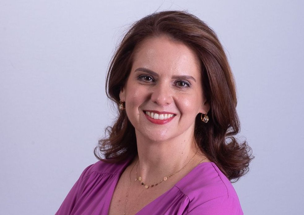 Imagem da procuradora-geral de Justiça Elaine Cardoso. Ela tem cabelos castanhos, pele clara e está vestida com uma blusa lilás.