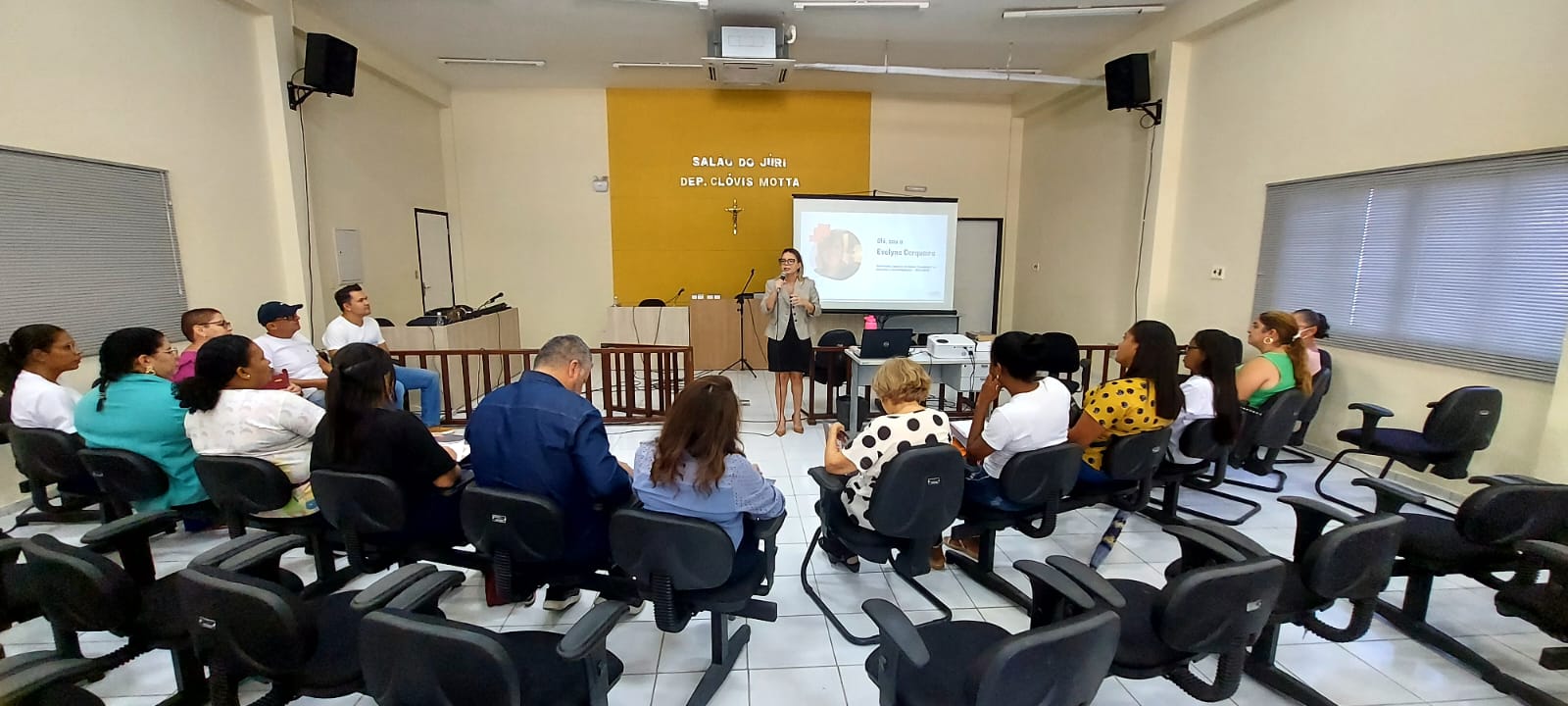 Imagem com várias pessoas sentadas em semi-círculo, assistindo a uma palestra