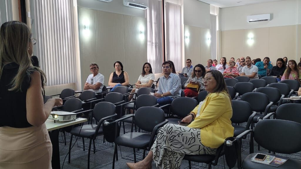 Imagem de uma mulher falando para pessoas em um auditório