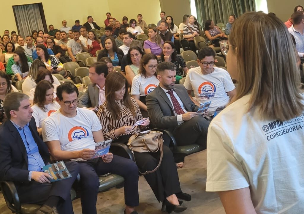 Imagem de um auditório repleto de pessoas, durante uma audiência pública.