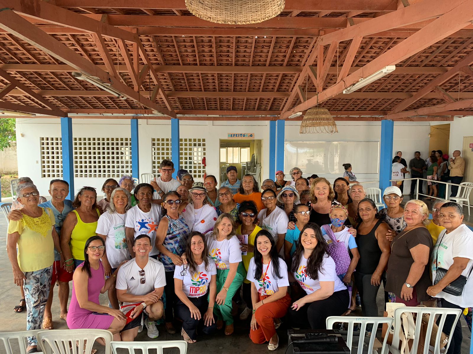 Imagem de várias pessoas, em um pátio, durante evento em uma instituição de longa permanência para pessoas idosas.