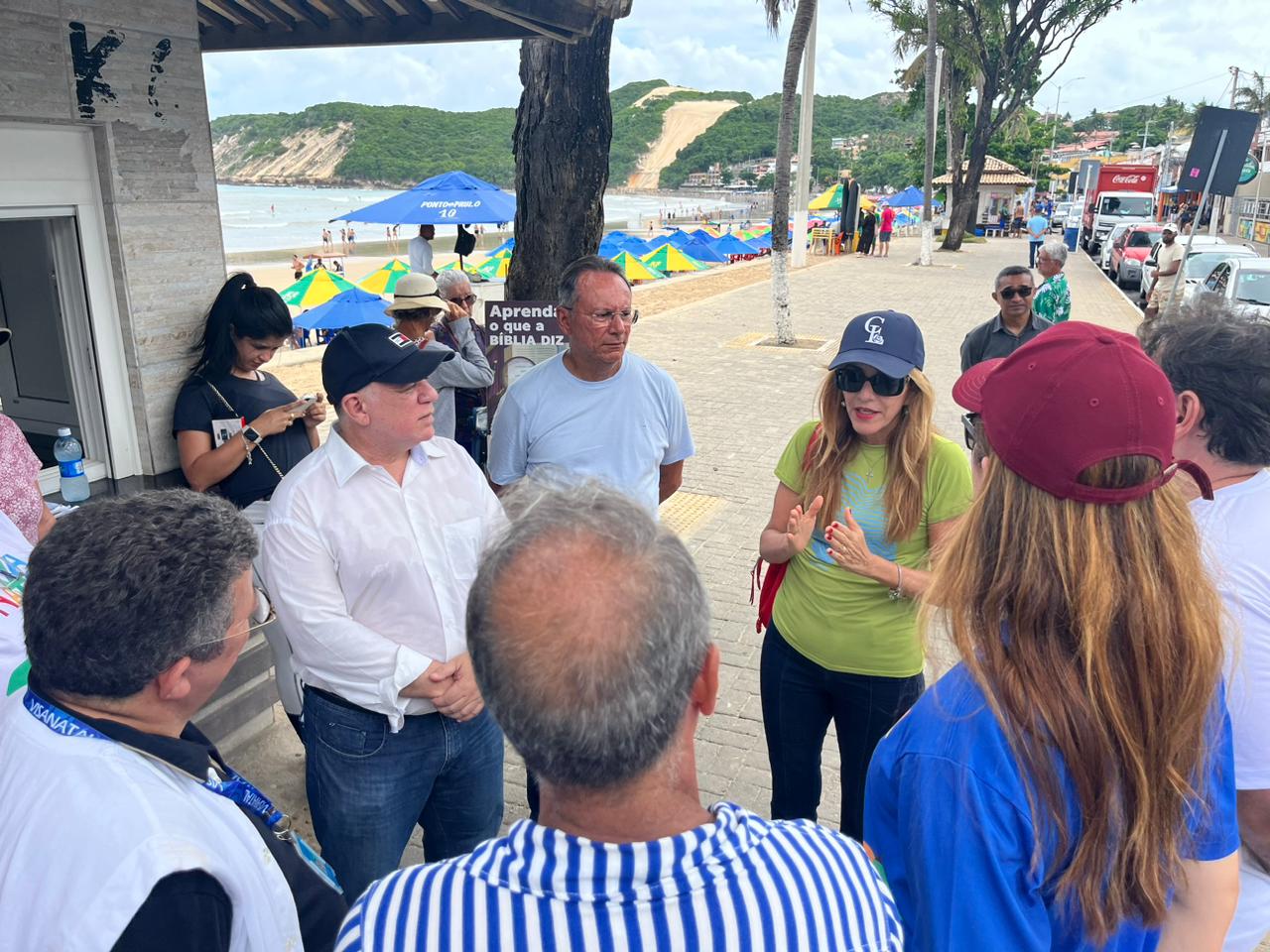 Imagem feita no calcadão da praia de ponta negra com o morro do careca aos fundos e no primeiro plano autoridades conversando em circulo.
