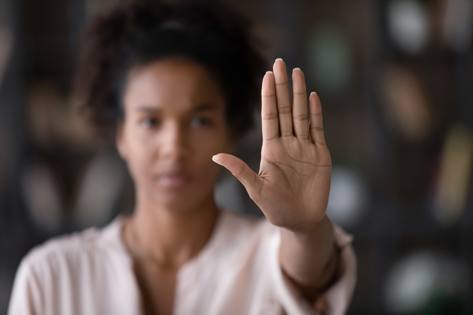 imagem de mulher desfocada com a mão levantada em sinal de pare