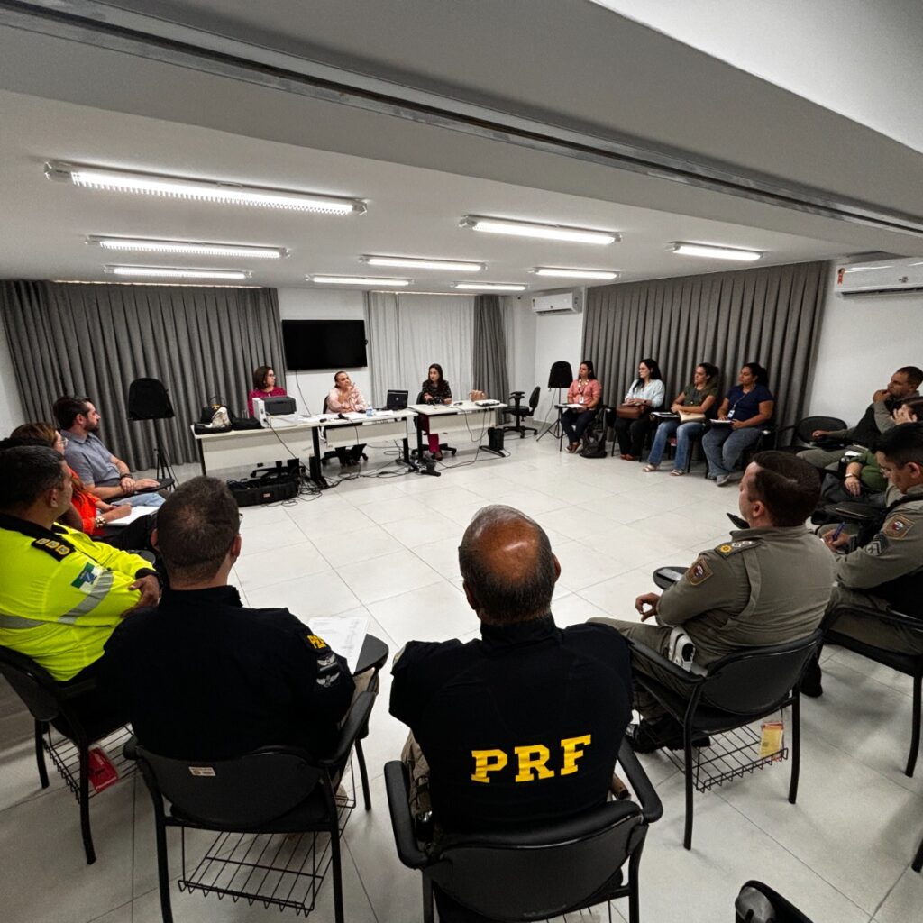 Pessoas sentadas em uma sala participando de uma reunião