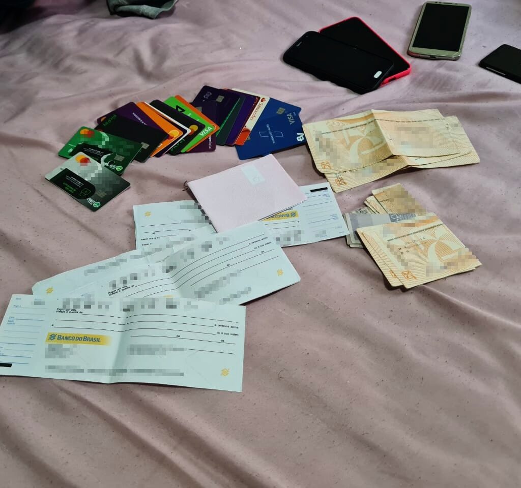 Imagem de aparelhos celulares, cheques e cartões de crédito em cima de uma cama