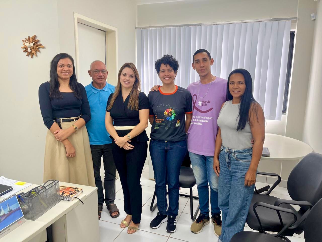 imagem com seis pessoas em pé em uma sala após a reuniao