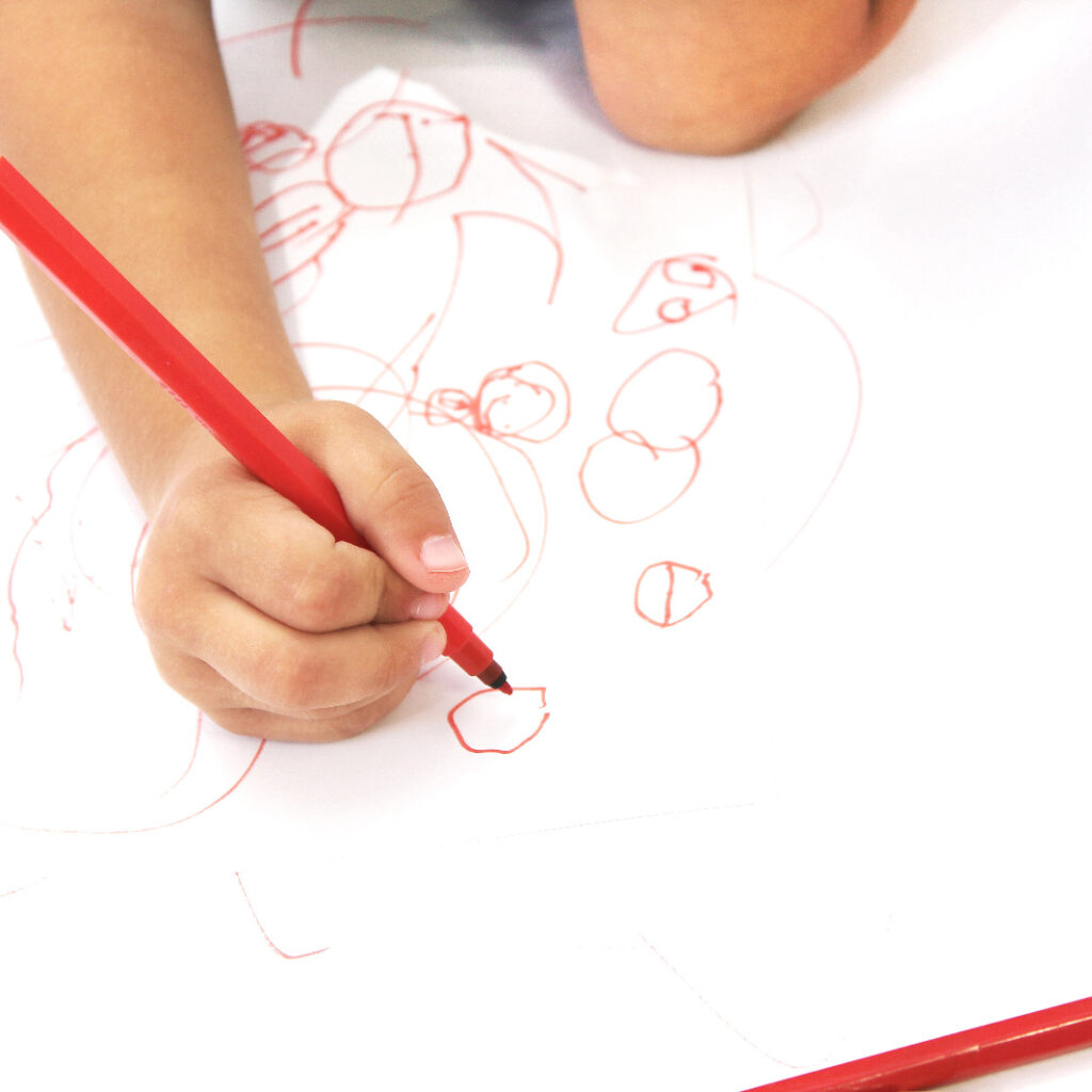 criança desenhando com caneta verm