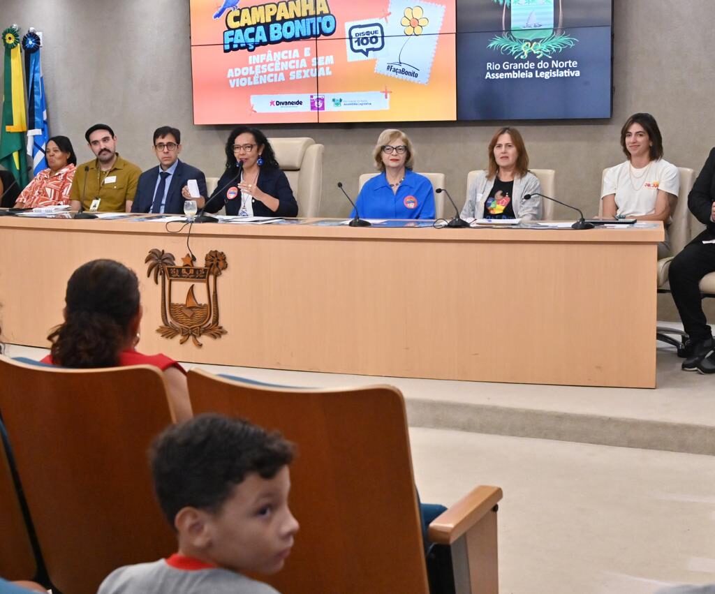 Uma mesa composta por nove autoridades e palestrantes durante um evento na Assembleia Legislativa do Rio Grande do Norte sobre a campanha "Faça Bonito", contra a violência sexual infantil, com público sentado em primeiro plano.