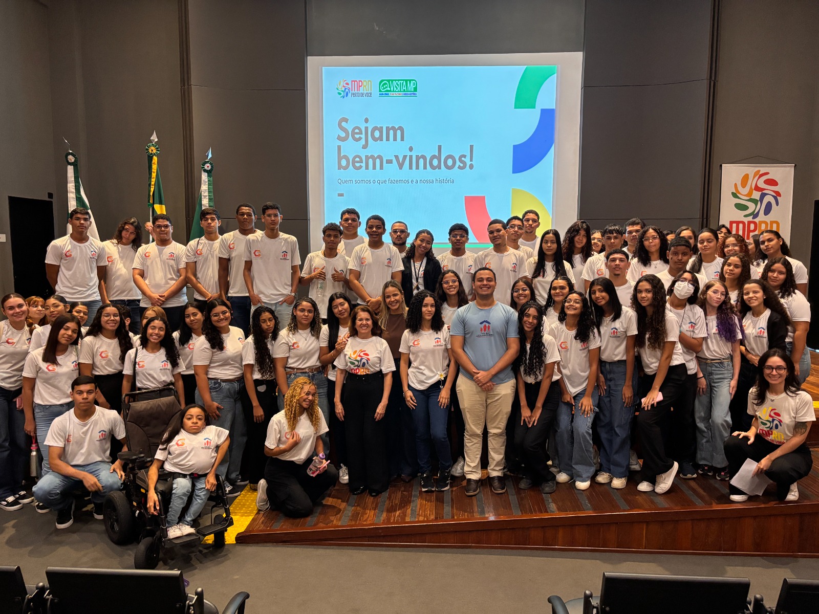 Alunos da Casa do Menor trabalhador em pé no palco do auditorio do mprn