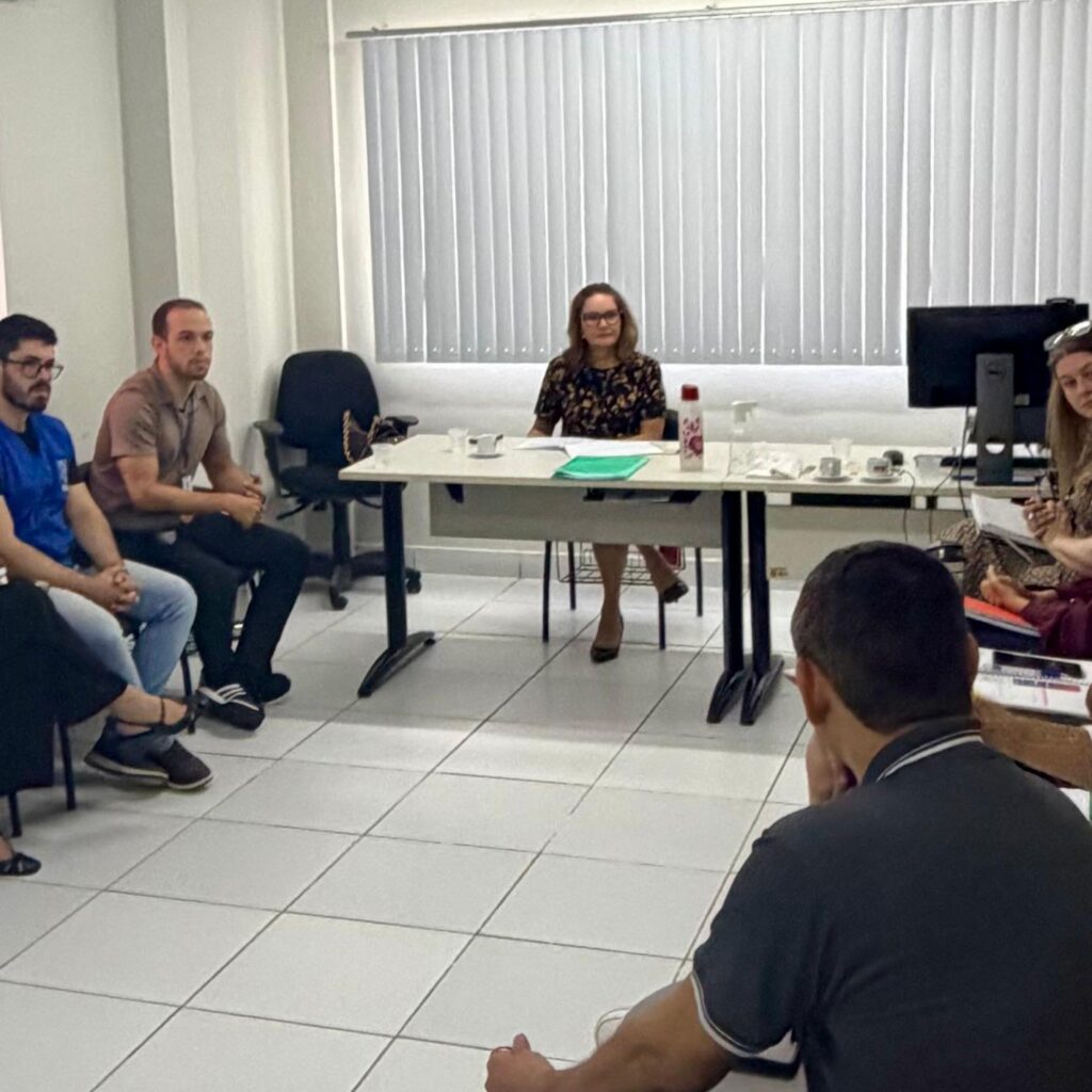 pessoas sentadas em uma sala com a promotora ao centro.