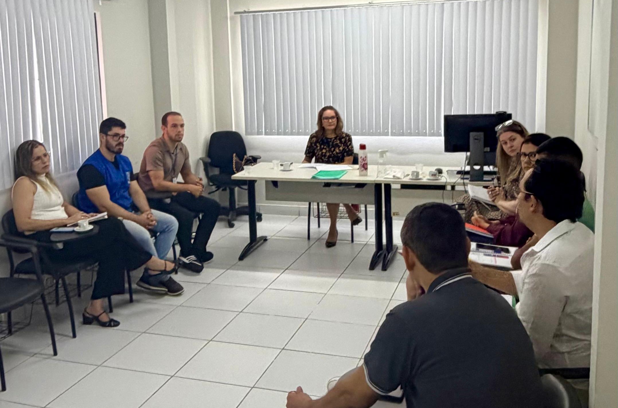 pessoas sentadas em uma sala com a promotora ao centro.