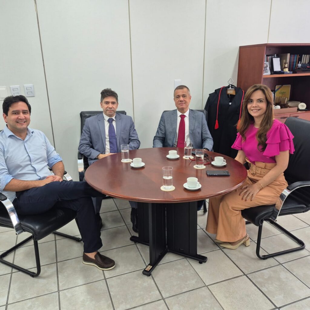 quatro pessoas sentadas ao redor de uma pessoa de reuniao