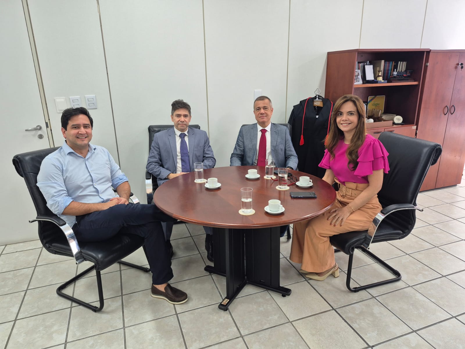 quatro pessoas sentadas ao redor de uma pessoa de reuniao