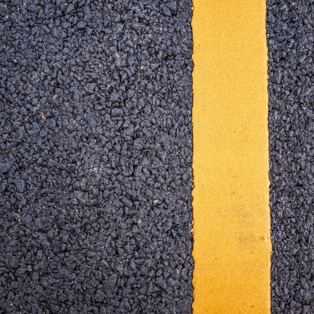 pista com asfalto escuro com faixa amarela pintada do lado esquerdo.