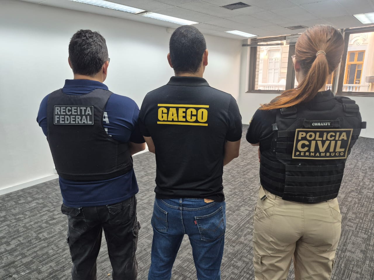tres pessoas de costas em uma sala vazia